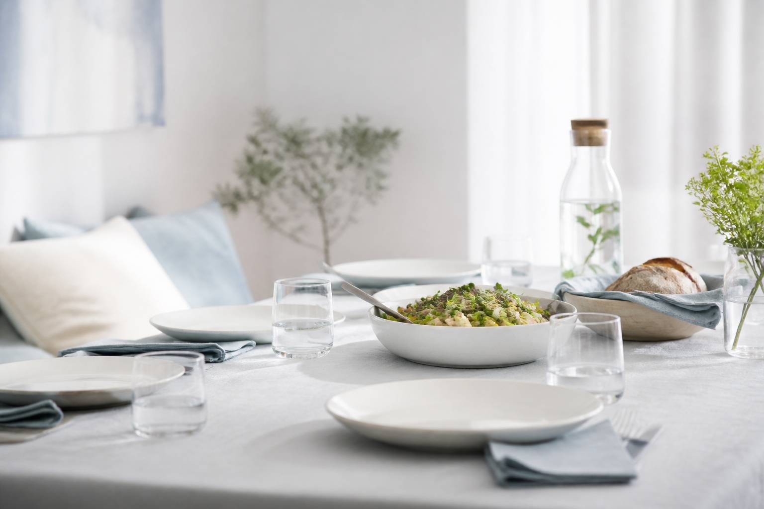 Table de repas dressee simplement avec assiettes, verres d'eau et pain